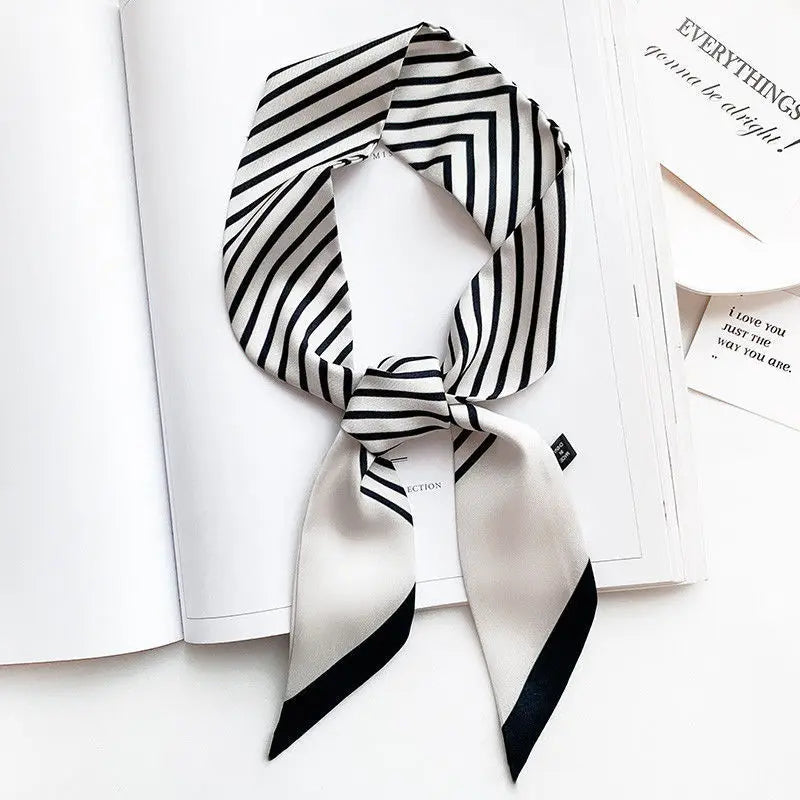Foulard de soie rayé noir et blanc noué en nœud, présenté sur une page blanche.