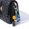 Black quilted pouch with a gold hardware keychain charm featuring colorful dice.