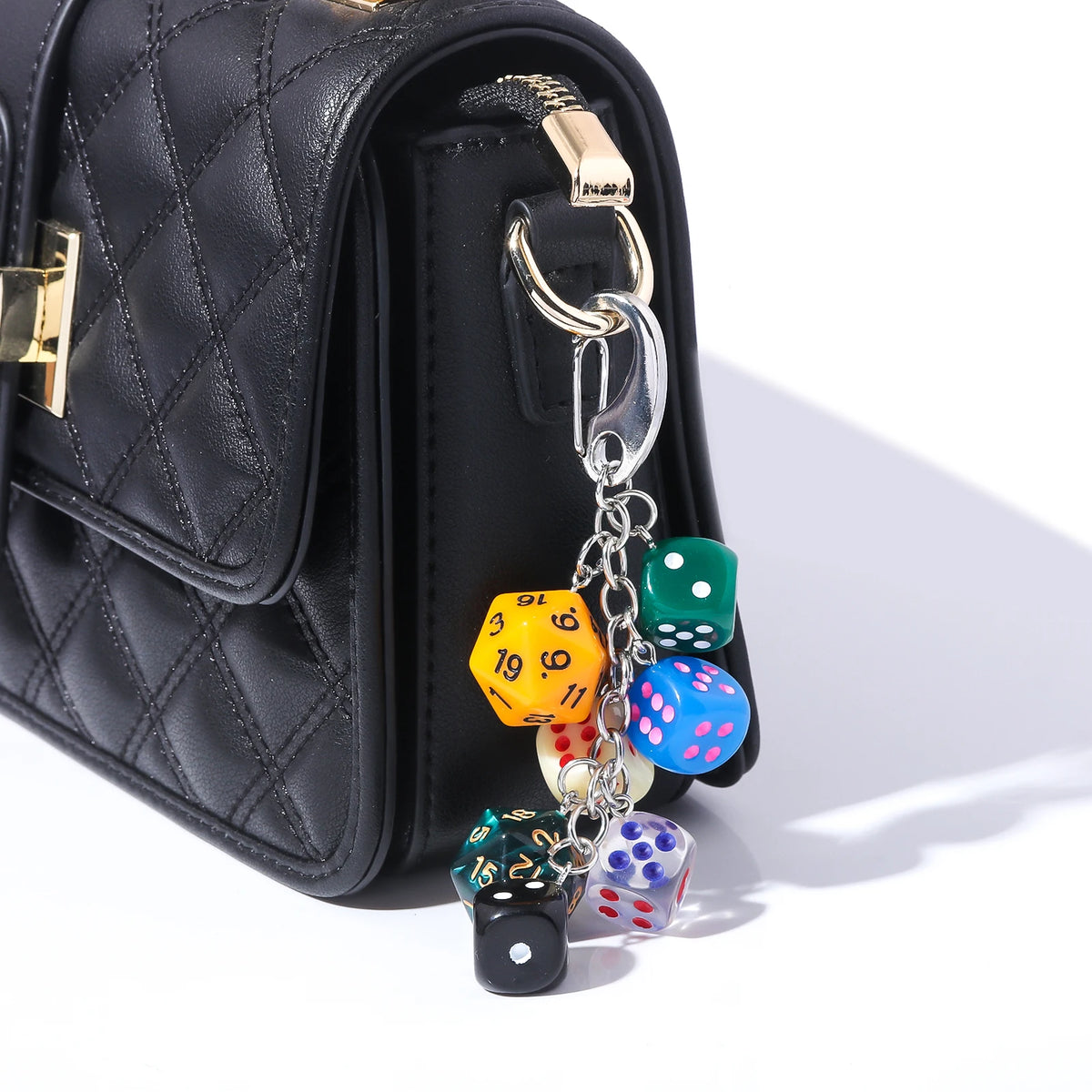 Black quilted pouch with a gold hardware keychain charm featuring colorful dice.