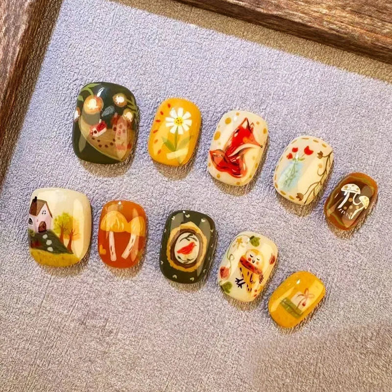 A collection of 12 cute cartoon press-on nails in various colors and designs displayed on a gray surface.