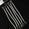 Multiple strands of elegant pearl straps with gold clasps displayed on a black surface.