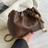 A brown PU leather chain shoulder bag with a gold chain strap is held in a hand against a white background.