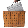 A brown leather handbag is shown with a gray fabric purse organizer insert placed on top.