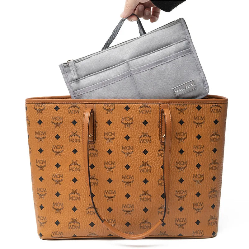 A brown leather handbag is shown with a gray fabric purse organizer insert placed on top.