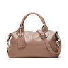 A tan faux leather Boston handbag with a top handle and gold hardware, shown from the front.