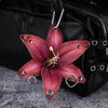 A realistic deep pink orchid flower keychain hanging from a black leather bag.