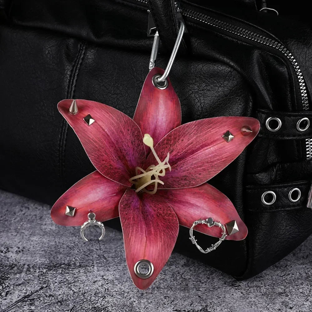 A realistic deep pink orchid flower keychain hanging from a black leather bag.
