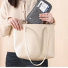 Una mujer sostiene un bolso tote de cuero beige y una cartera para pasaporte que bloquea RFID.