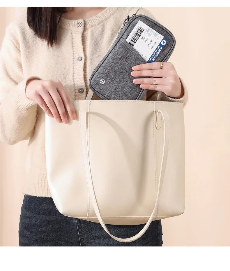 Una mujer sostiene un bolso tote de cuero beige y una cartera para pasaporte que bloquea RFID.