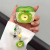 A hand holds a green apple shaped earphone case with a yellow interior and a dangling charm.