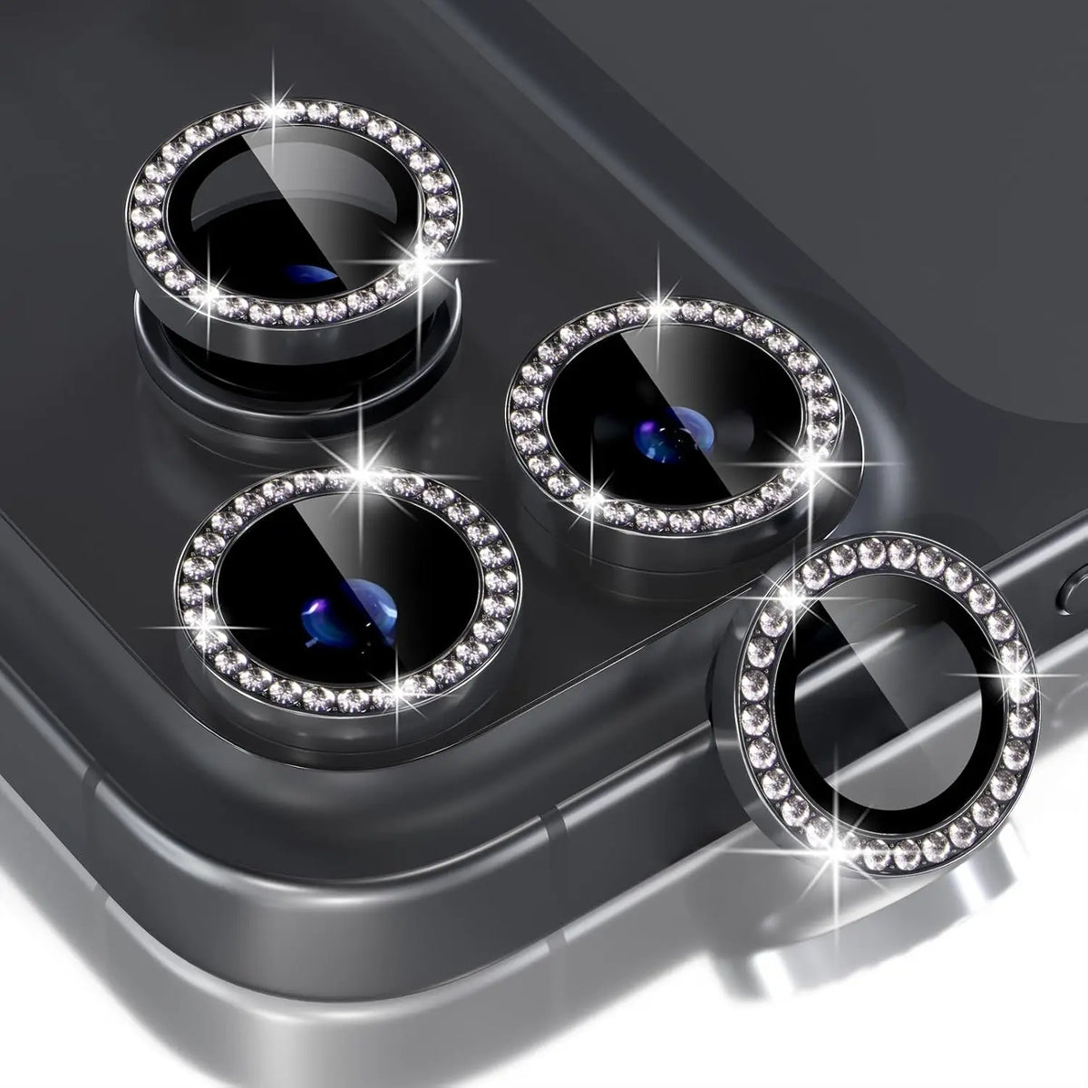A close-up view of a silver glitter diamond camera lens protector with a metal frame for an iPhone, showing four lenses.