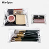 A set of three cosmetic or tool items packaged in transparent portable organizer pouches.