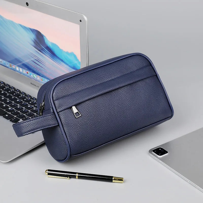 A navy blue PU leather crossbody bag is shown next to a laptop and a pen on a light gray surface.