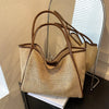 A beige straw woven tote bag with brown PU trim displayed next to a matching pouch.