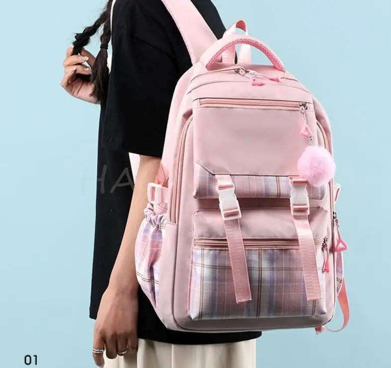 A pink canvas backpack with a plaid pattern is worn by a person.