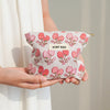 A hand holds a pink floral canvas makeup bag with the text DIDF BAG on it.