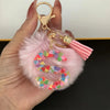 A hand holds a custom initial letter keychain featuring a shiny resin pendant and pink alphabet charm.