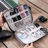 A portable travel cable organizer pouch with multiple tools and accessories is shown open on a wooden surface.