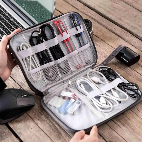 A portable travel cable organizer pouch with multiple tools and accessories is shown open on a wooden surface.