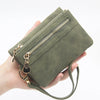 Una mano sostiene una cartera de cuero PU retro plegable verde oliva con herrajes dorados.