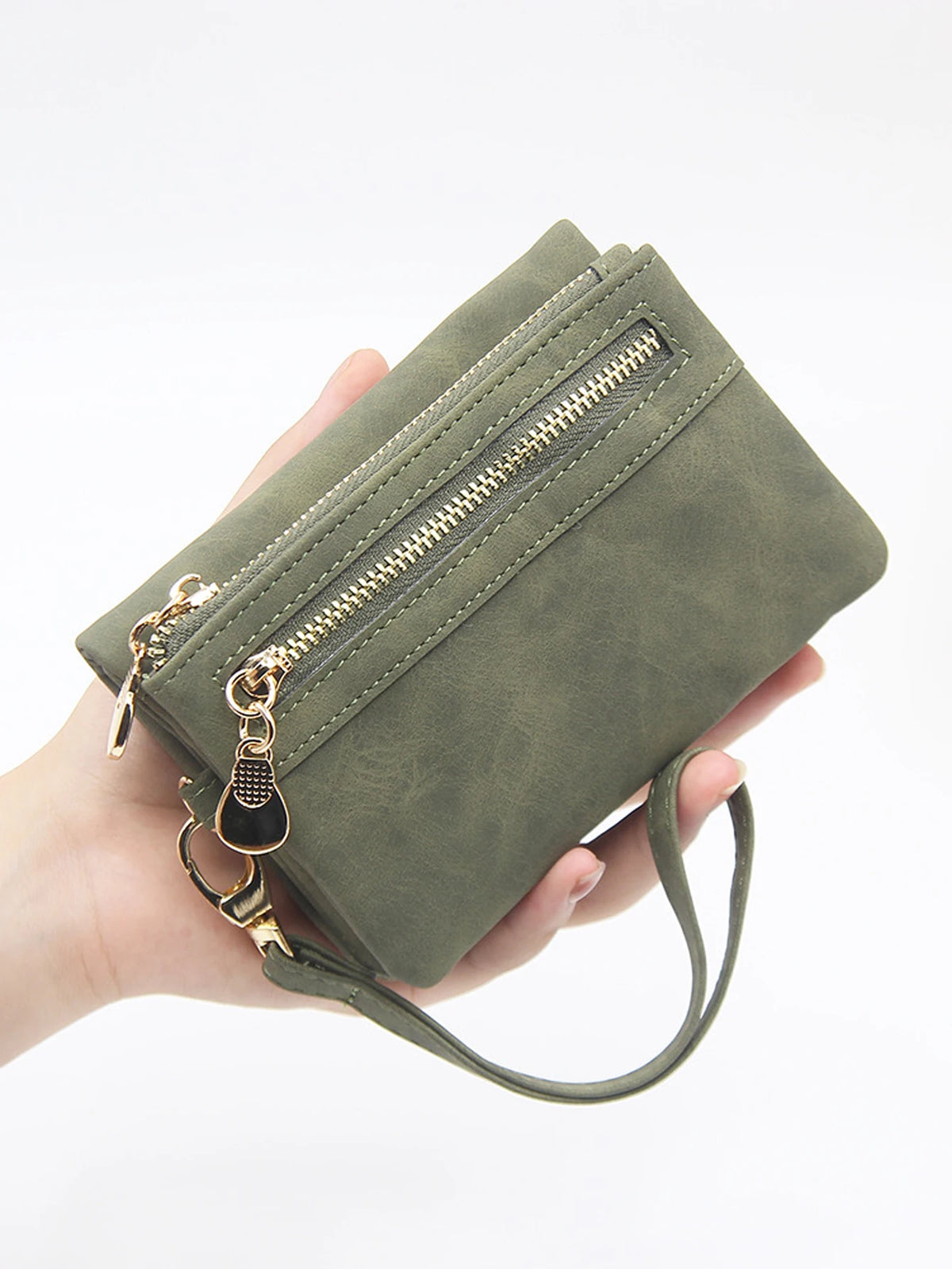 Una mano sostiene una cartera de cuero PU retro plegable verde oliva con herrajes dorados.
