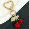 Gold heart-shaped bag charm with a lobster clasp and a dangling cherry blossom design.