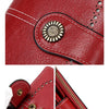 A close-up of a red leather wallet featuring a gold-toned metal emblem and stitching, shown alongside the folded structure.