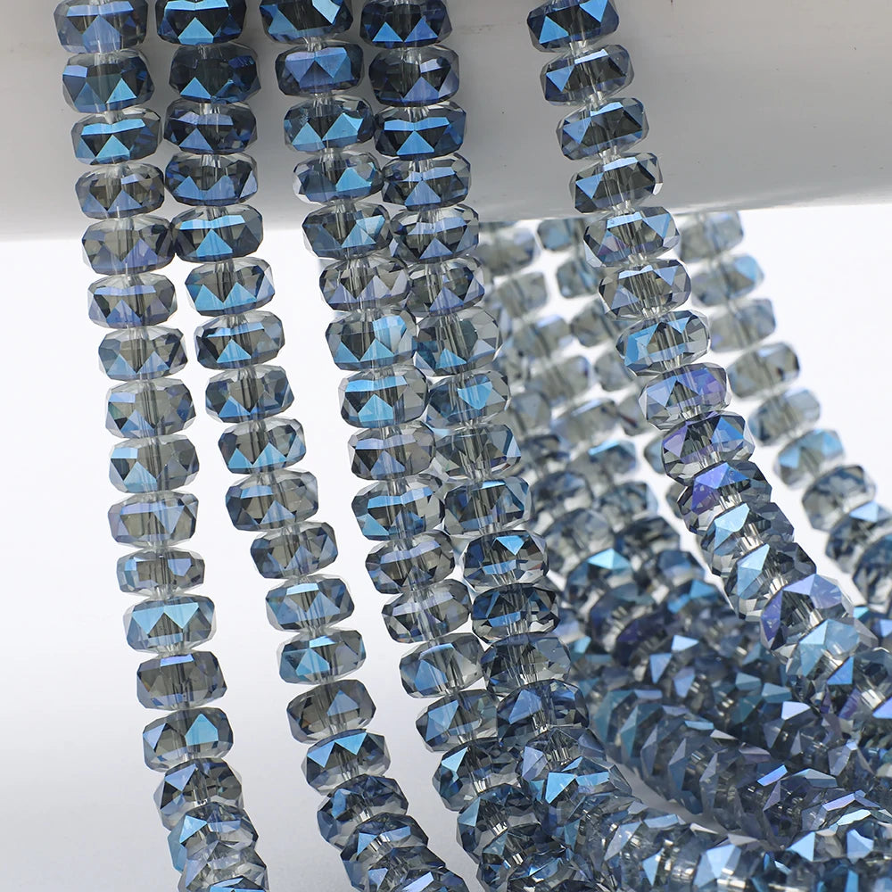 A close-up of blue and clear faceted crystal glass beads strung together for jewelry making.
