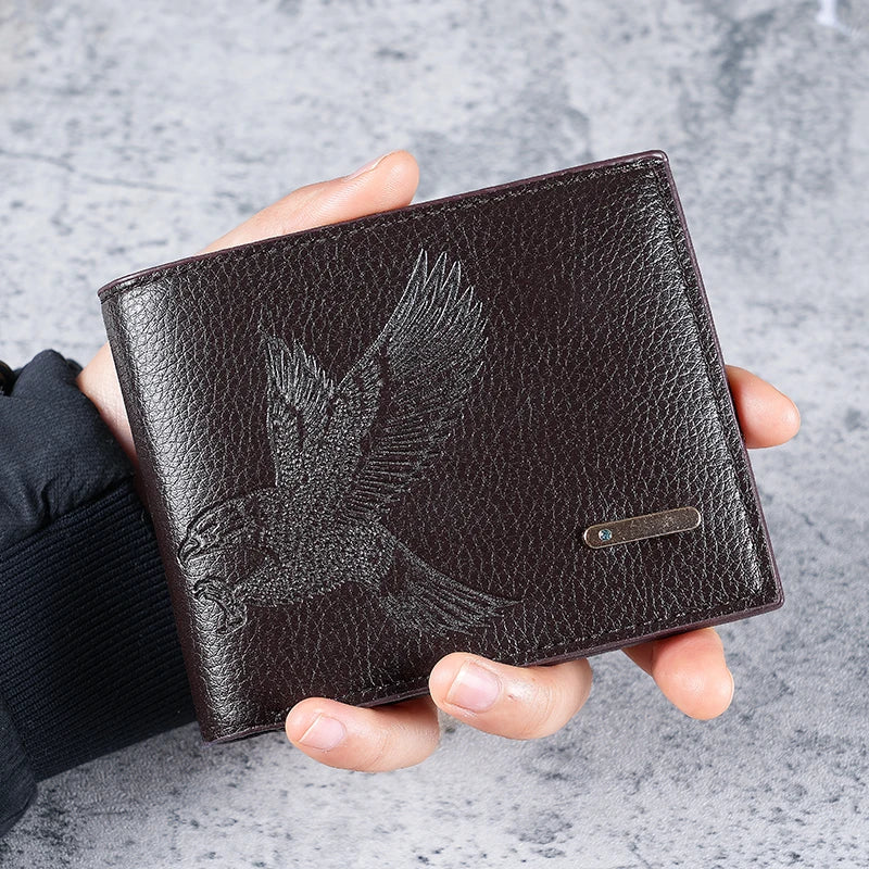 A dark brown leather wallet with an embossed eagle design is held in a person's hand.