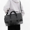 A black leather-trimmed travel duffle bag carried by a person wearing a white hooded jacket.