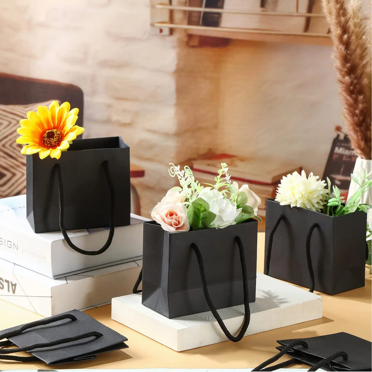 Bolsas de regalo de papel grueso negro con asas de cuerda exhibidas sobre una superficie de madera.