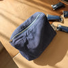 Pochette de rangement cosmétique à motif à carreaux bleu marine posée sur une surface en bois clair avec d'autres petits obje