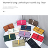 A collection of women's long cowhide purses in various colors and styles displayed on a white table.