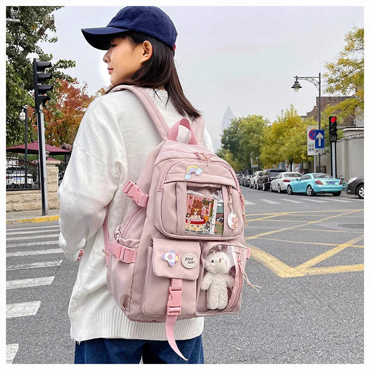 A woman wearing a white sweater and jeans carries a pink backpack on a city street.