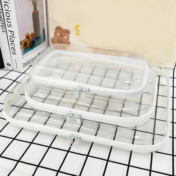 A clear plastic storage pouch set with a lid and a base, displayed on a black and white grid surface.