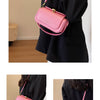 A pink retro textured leather shoulder bag carried by a person in a black coat.