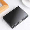 A black slim card holder wallet with a silver clasp is shown on a white surface next to a wooden item.