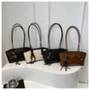 A row of four large capacity black and beige PU leather tote bags with leather handles displayed on a white surface.