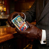A hand in a suit jacket holds a vintage metal card holder and wallet on a wooden bar top.