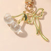 Pendentif clé en forme de feuille dorée avec deux pierres rondes et scintillantes claires.