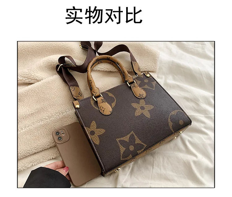 A dark brown ladies' shoulder tote bag with tan leather handles and gold hardware resting on a light beige fabric.