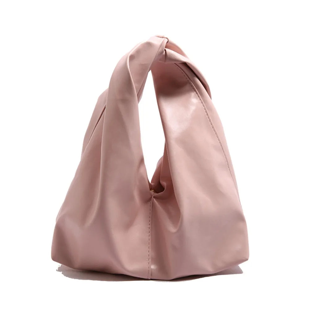 A light pink leather minimalist crossbody tote bag folded and displayed against a white background.