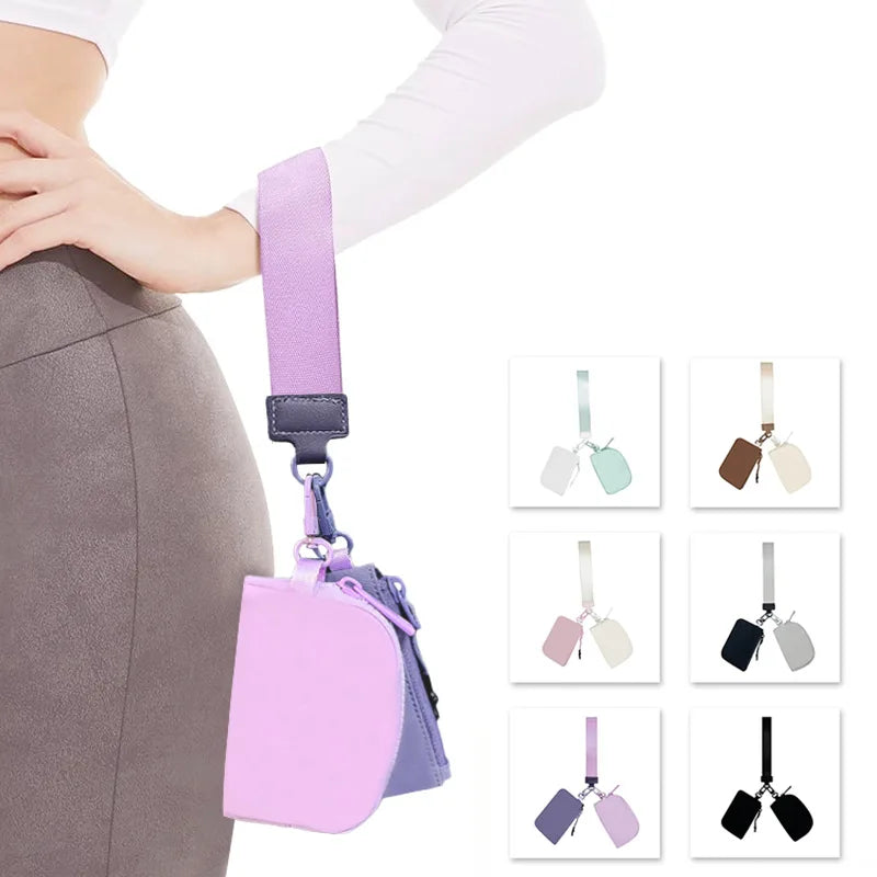 A purple mini nylon zip wristlet coin purse is shown being held by a person's hand.