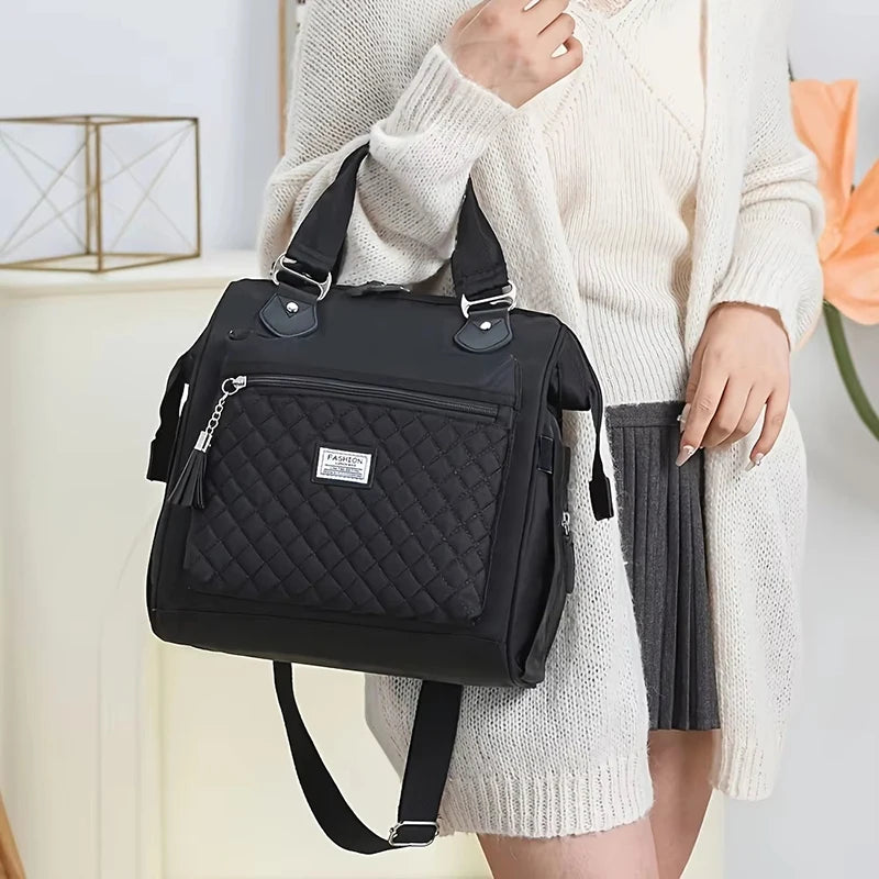 Une femme tient un sac de lunch isotherme noir avec une sangle à l'épaule sur un fond clair.