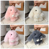 Three plush rabbit bag charms in pink, white, and gray are displayed with gold keyrings.