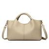 A beige luxury soft leather women's tote bag with tan leather handles and a stitched logo.