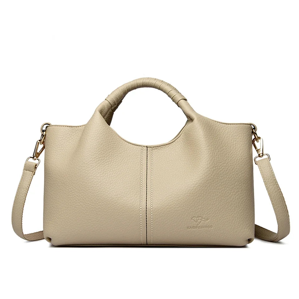A beige luxury soft leather women's tote bag with tan leather handles and a stitched logo.