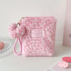 A pink faux fur makeup bag with a leopard print pattern and a pink pom-pom charm.
