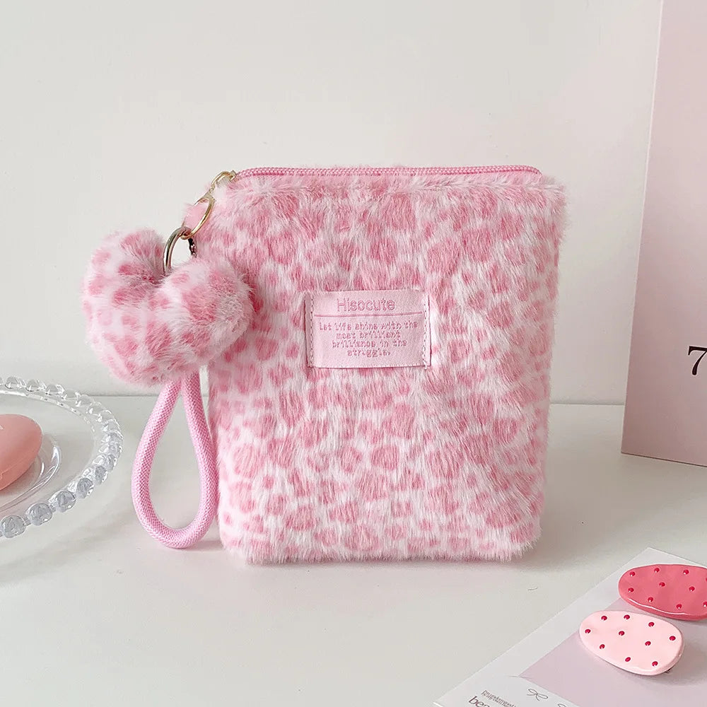 A pink faux fur makeup bag with a leopard print pattern and a pink pom-pom charm.