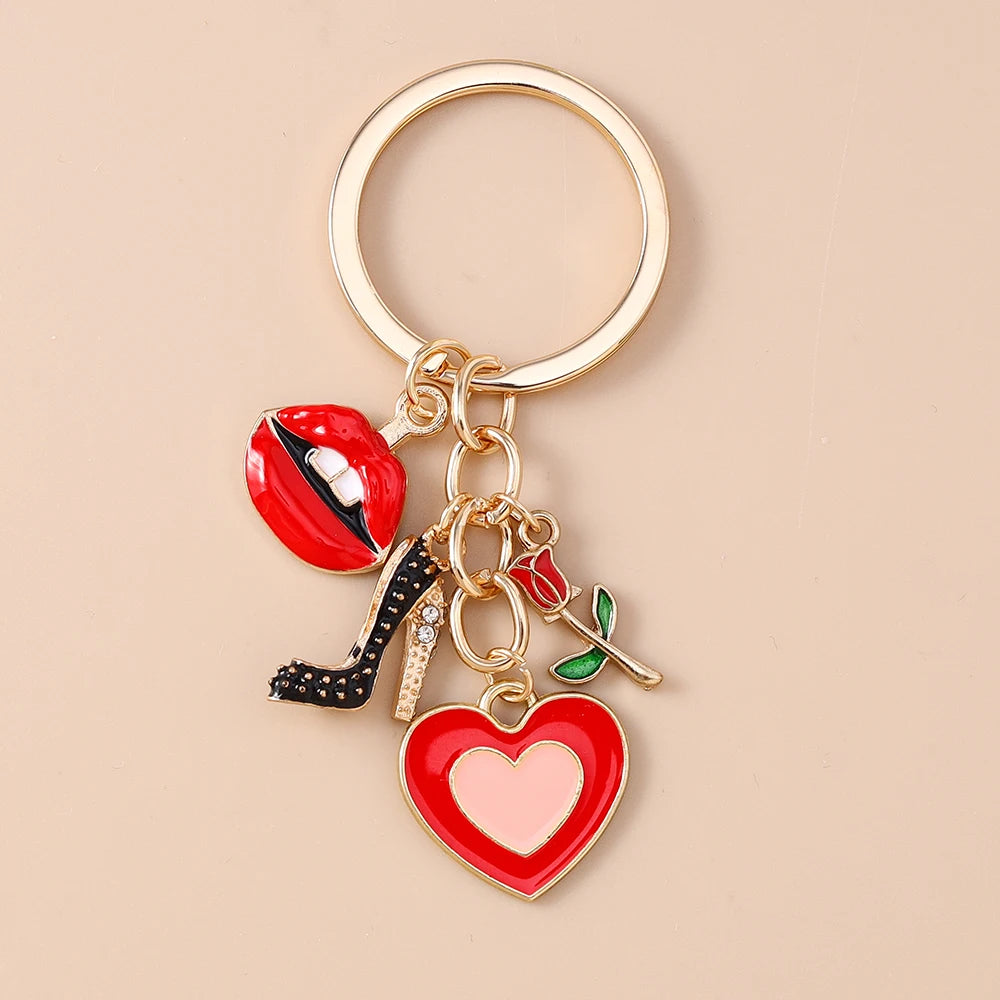 Gold-toned enamel heart keychain featuring a red lip, black high heel, and green leaf charms.